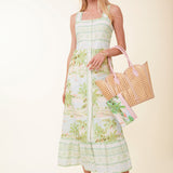Woman wearing a floral dress holding a woven bag on a beige background