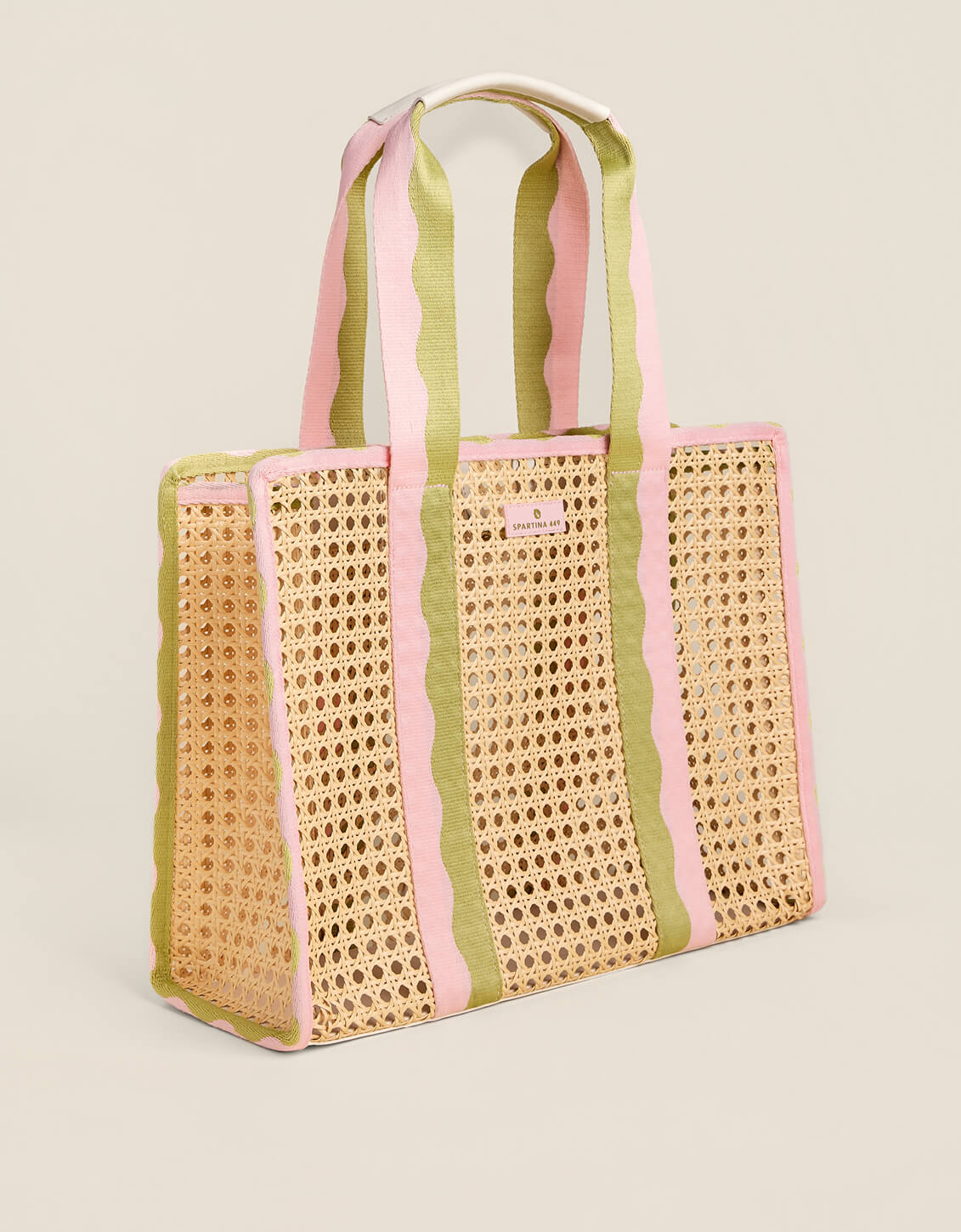 Woven tote bag with pink and green striped handles on a beige background