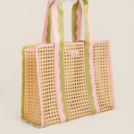 Woven tote bag with pink and green striped handles on a beige background