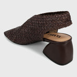 A dark brown woven slingback mule sandal with a chunky block heel, shown from a three-quarters angle on a light gray background. The brand name 'VINTA' is visible on the tan insole.