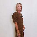 Woman wearing a brown dress against a white wall