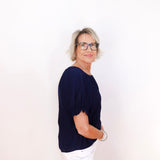 Person wearing a navy blue top and white pants on a plain background