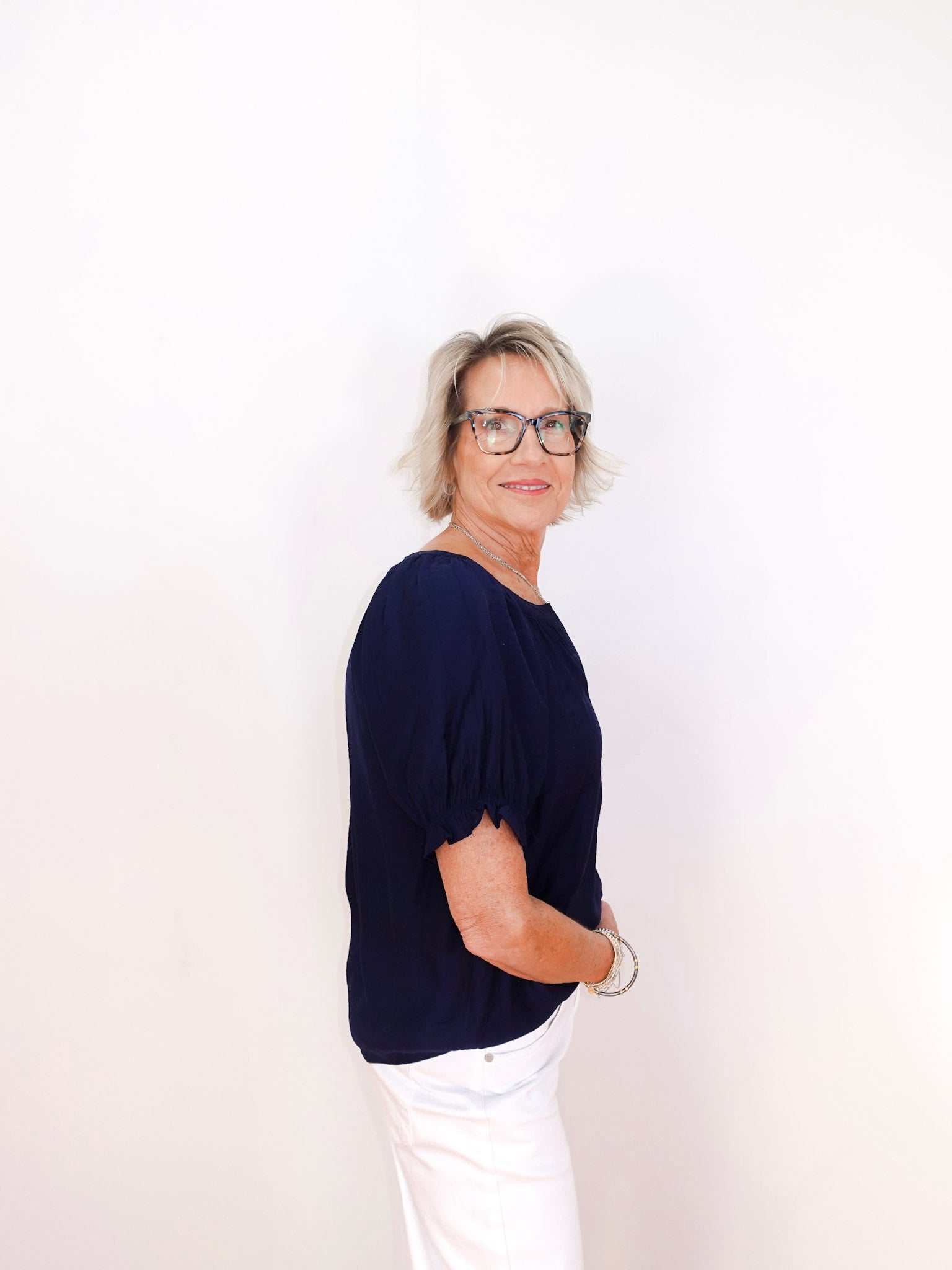 Person wearing a navy blue top and white pants on a plain background