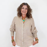 Woman wearing a beige shirt and white pants against a white background