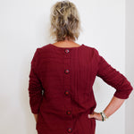 Person wearing a burgundy button-up shirt against a white background