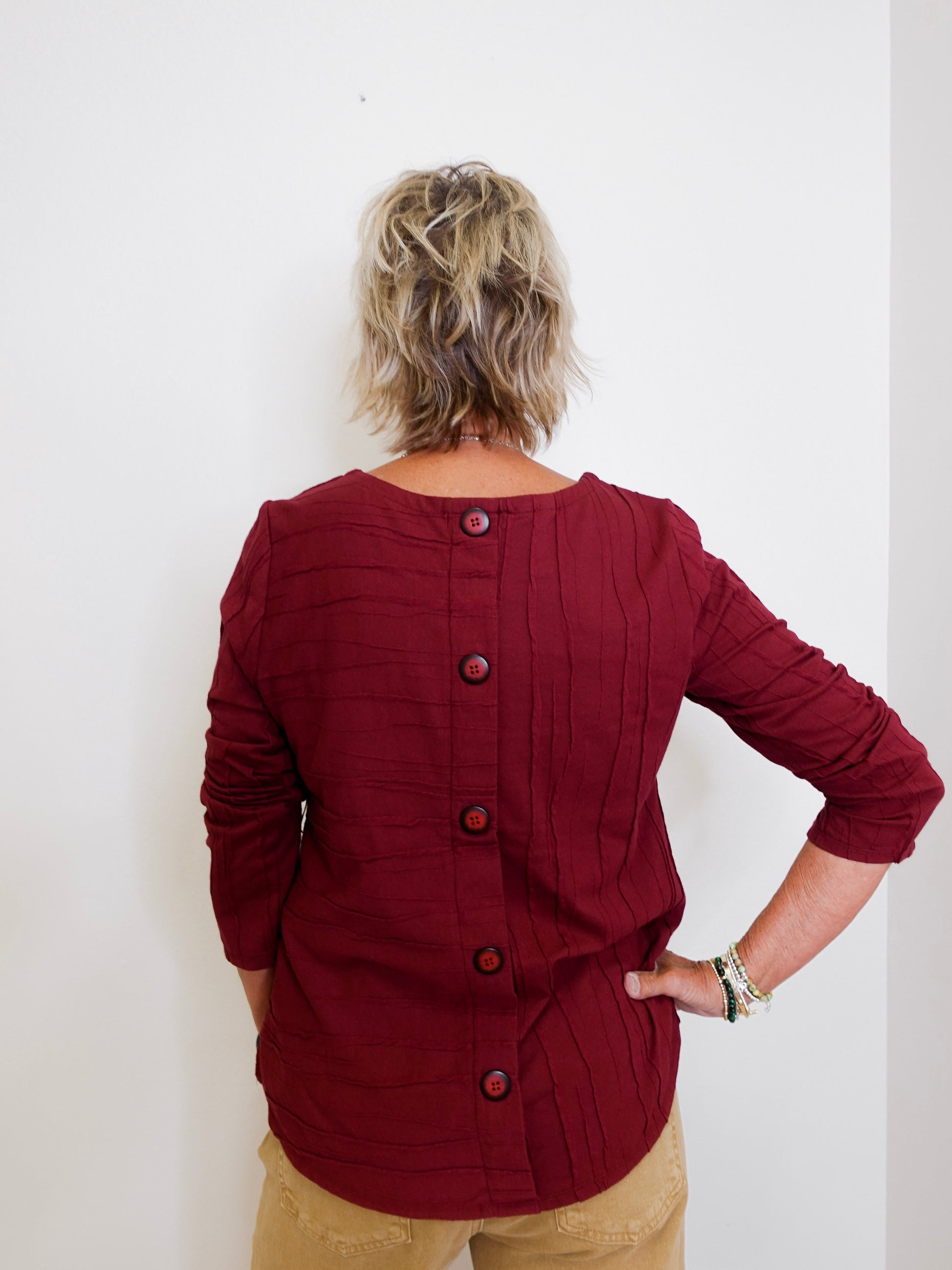 Person wearing a burgundy button-up shirt against a white background