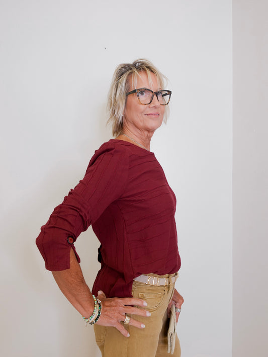 Person wearing a red shirt and beige pants against a white background