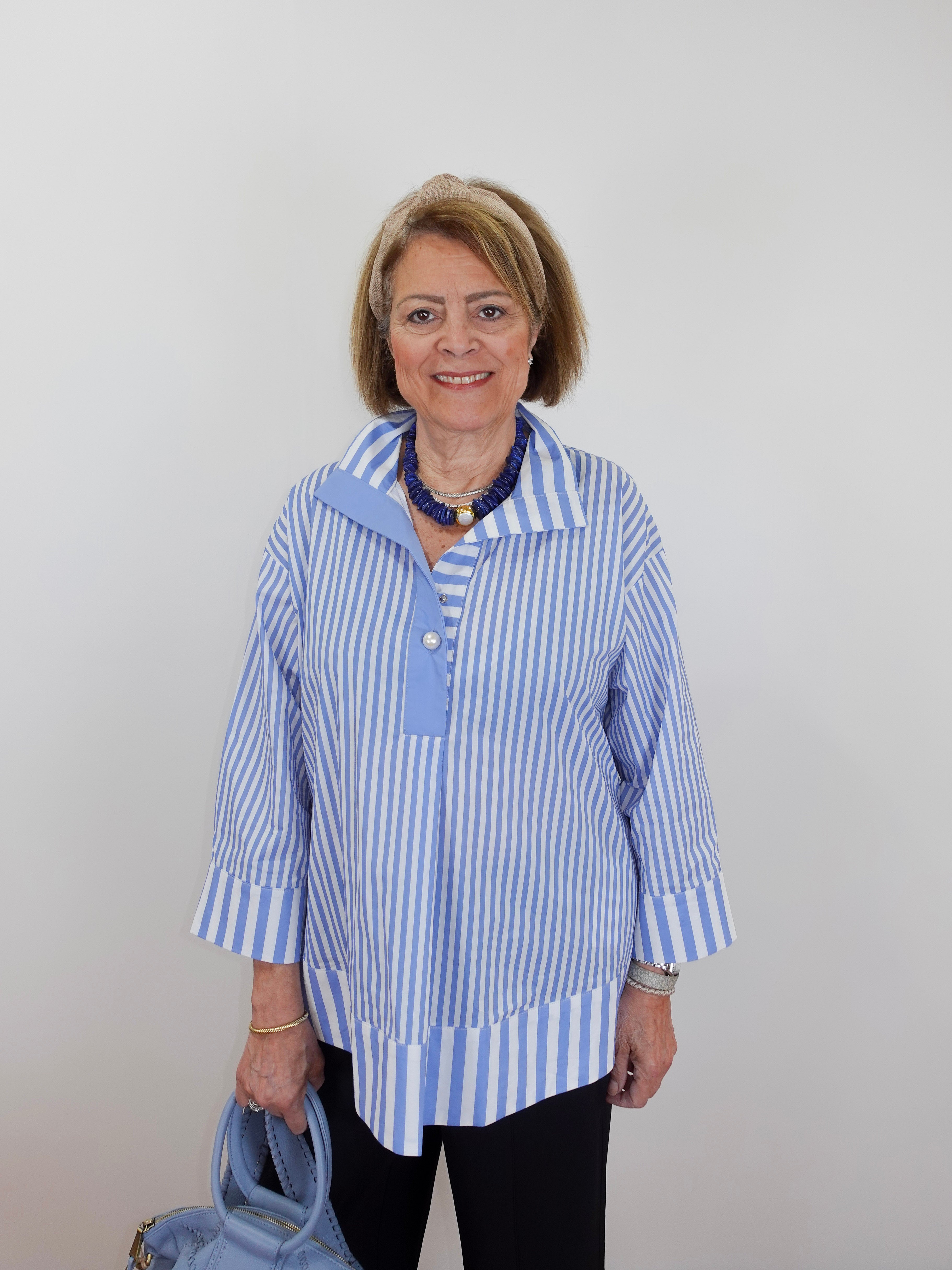 Woman wearing a blue and white striped shirt with a plain background