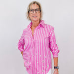 Person wearing a pink and white striped shirt against a plain background