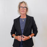 Person wearing a black pinstripe blazer over a blue shirt with a plain background