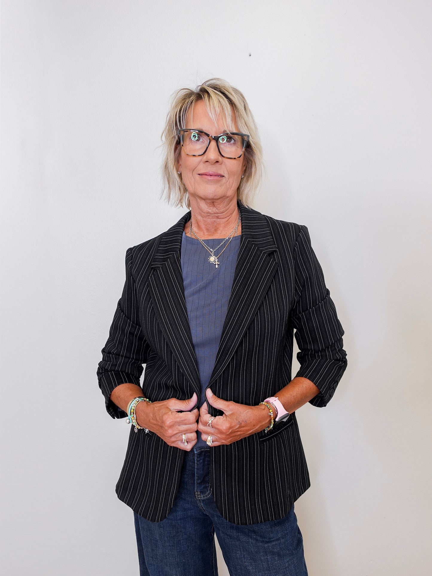 Person wearing a black pinstripe blazer over a blue shirt with a plain background