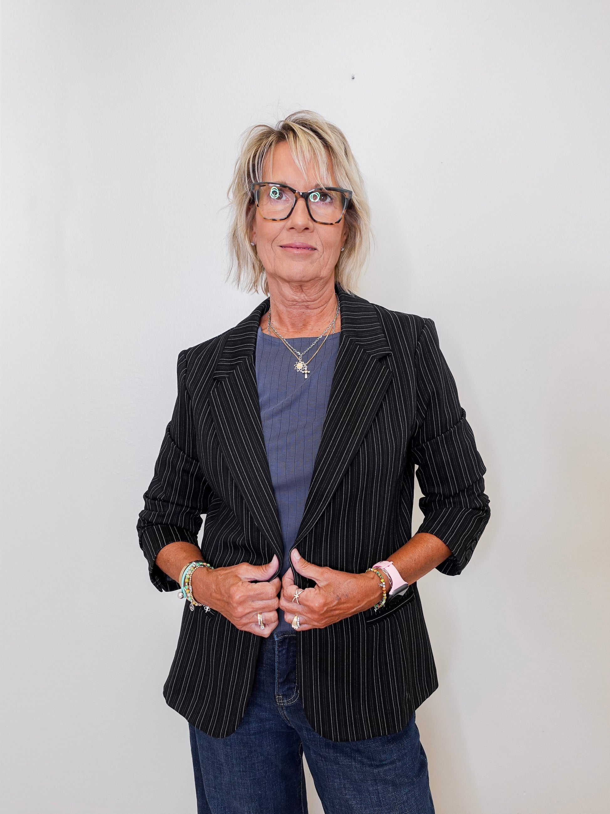 Person wearing a black pinstripe blazer over a blue shirt with a plain background