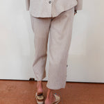Person wearing a beige suit with a white wall background