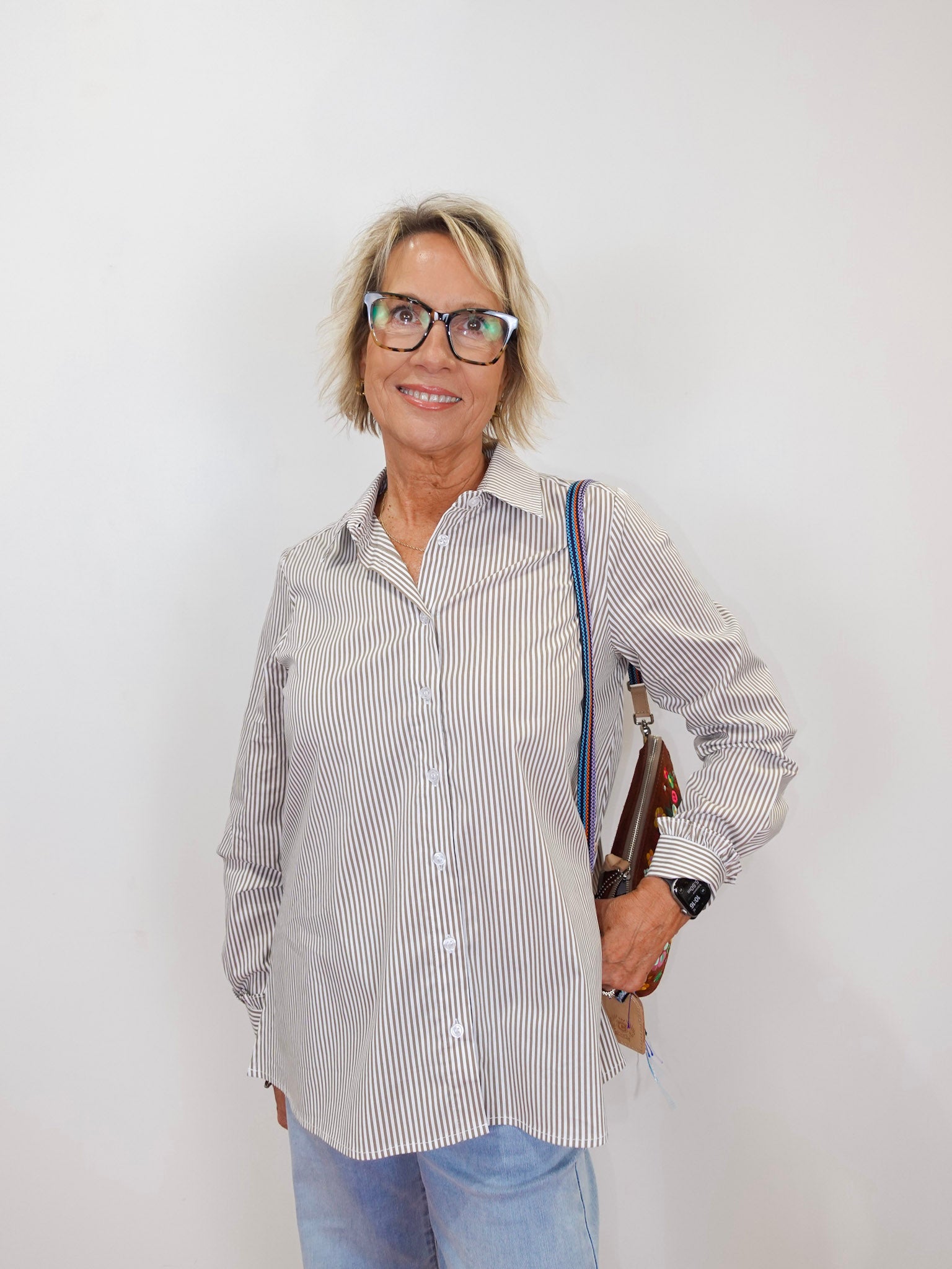 Woman wearing the Renuar striped long sleeve blouse with a classic button-front design.