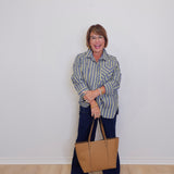 Woman holding a beige handbag against a white wall
