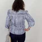 Person wearing a black and white striped blouse with puffed sleeves against a plain background
