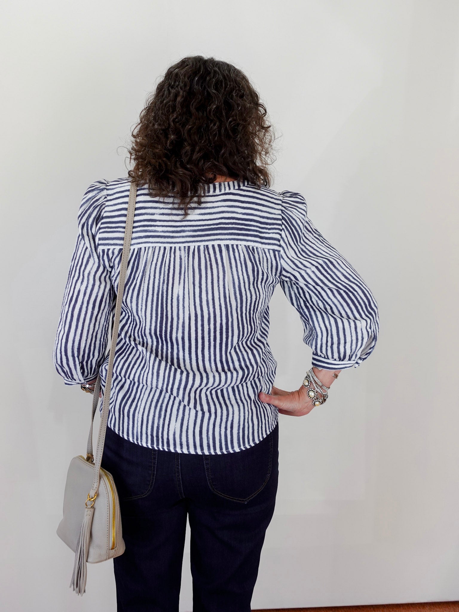 Person wearing a black and white striped blouse with puffed sleeves against a plain background