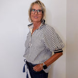 Woman wearing a black and white striped shirt with a plain background