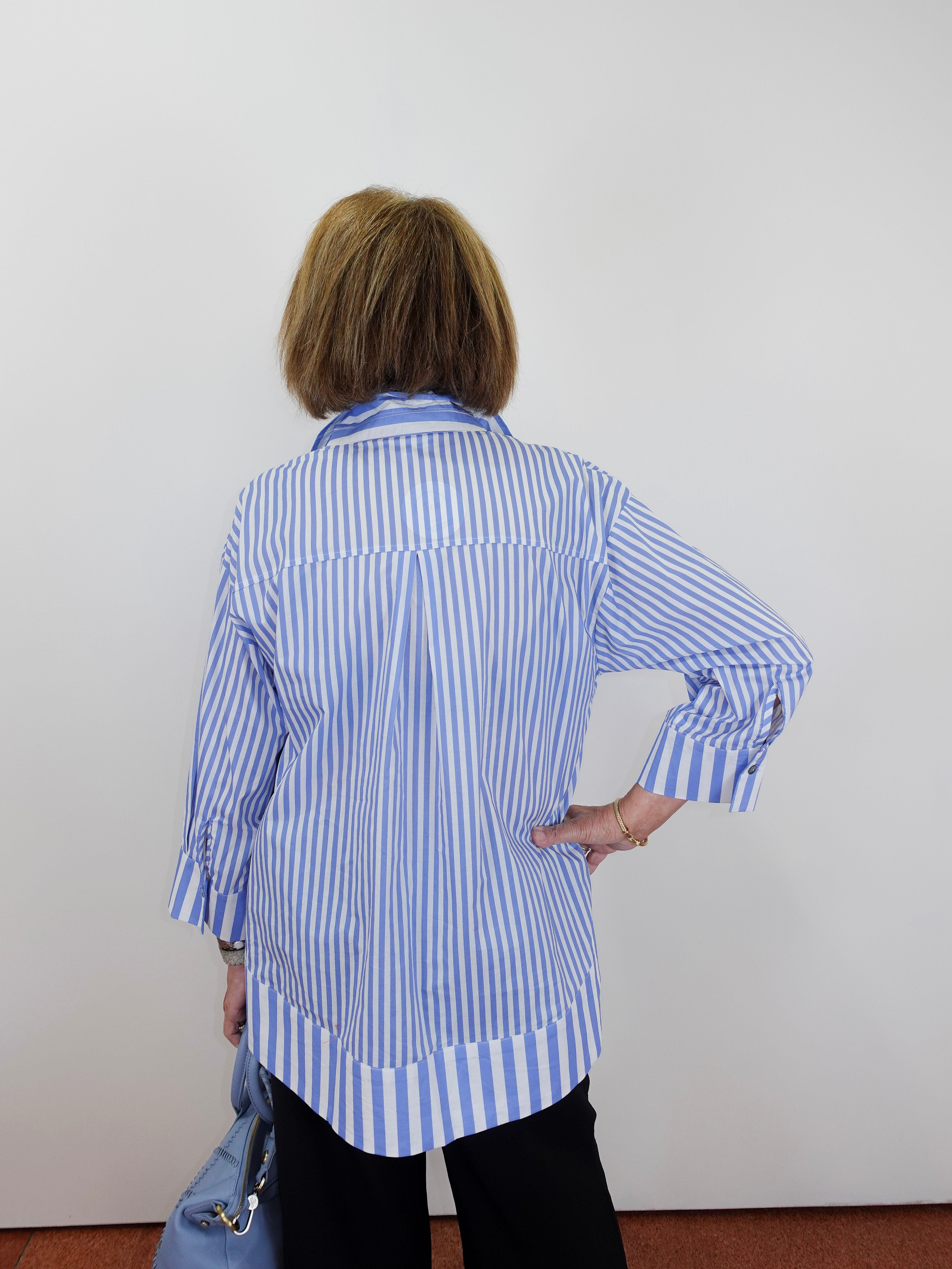 Person wearing a blue and white striped shirt against a plain background