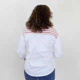 Person wearing a white shirt with a red and black striped pattern on the back, standing against a plain white wall.