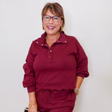 Woman wearing a burgundy outfit with glasses against a white background