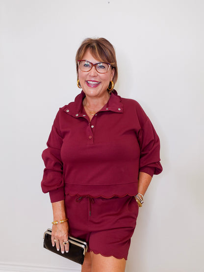 Woman wearing a burgundy outfit with glasses against a white background