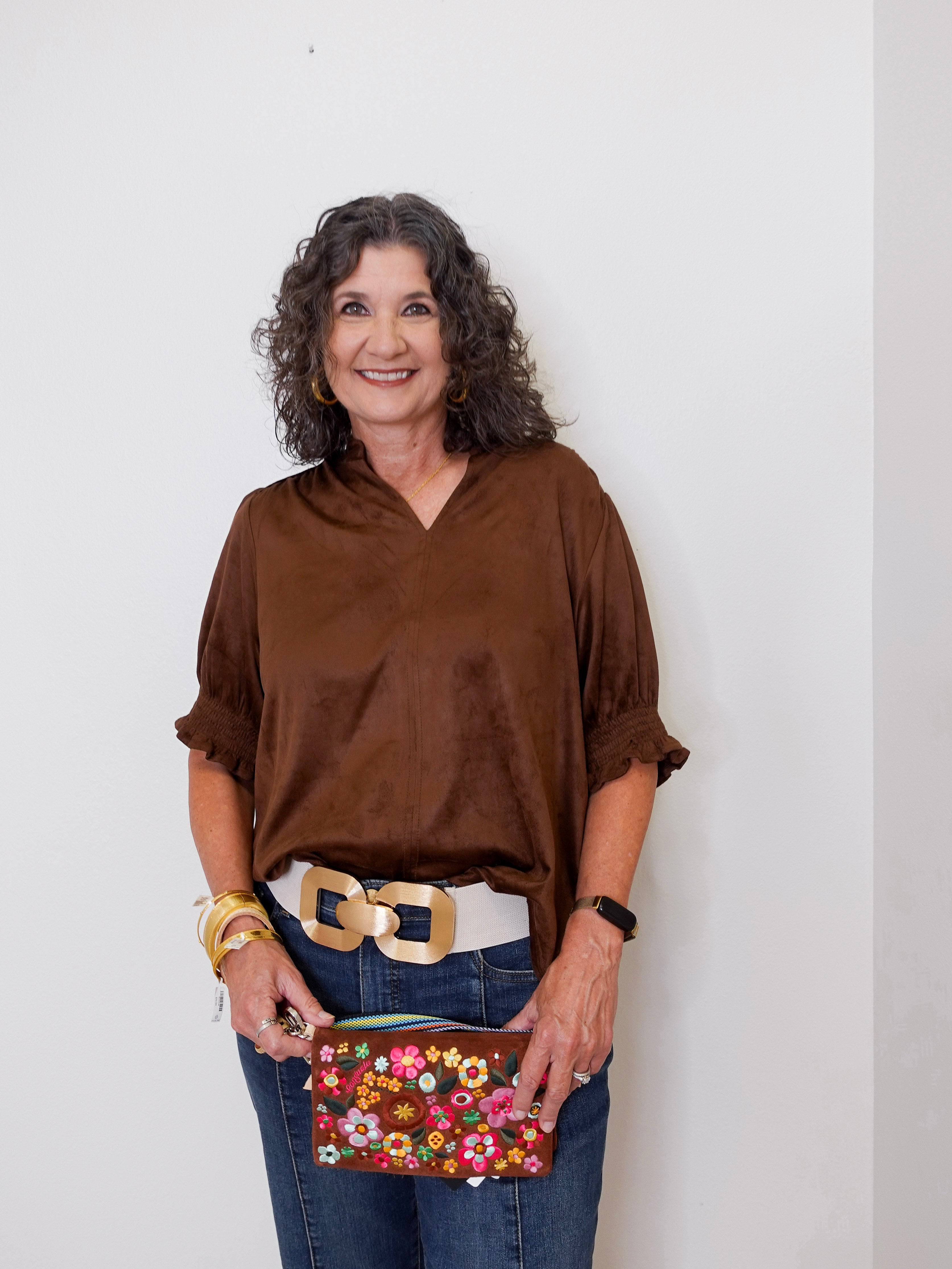 Woman holding a floral clutch against a white background
