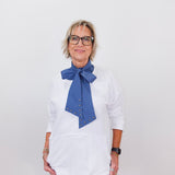 Person wearing a white blouse with a blue scarf against a white background