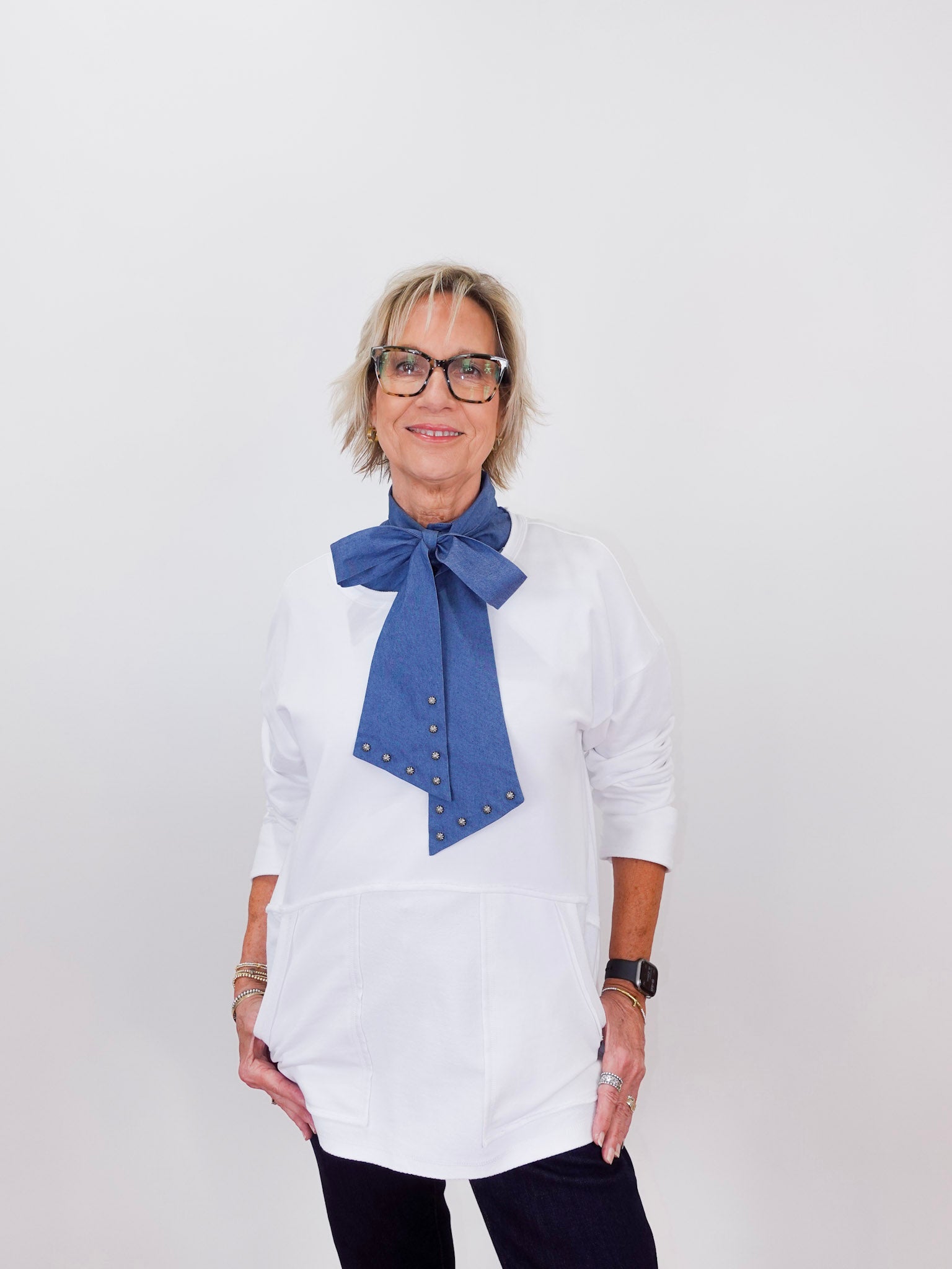 Person wearing a white blouse with a blue scarf against a white background