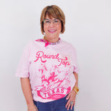Woman wearing a pink 'Round Top Texas' t-shirt against a white background