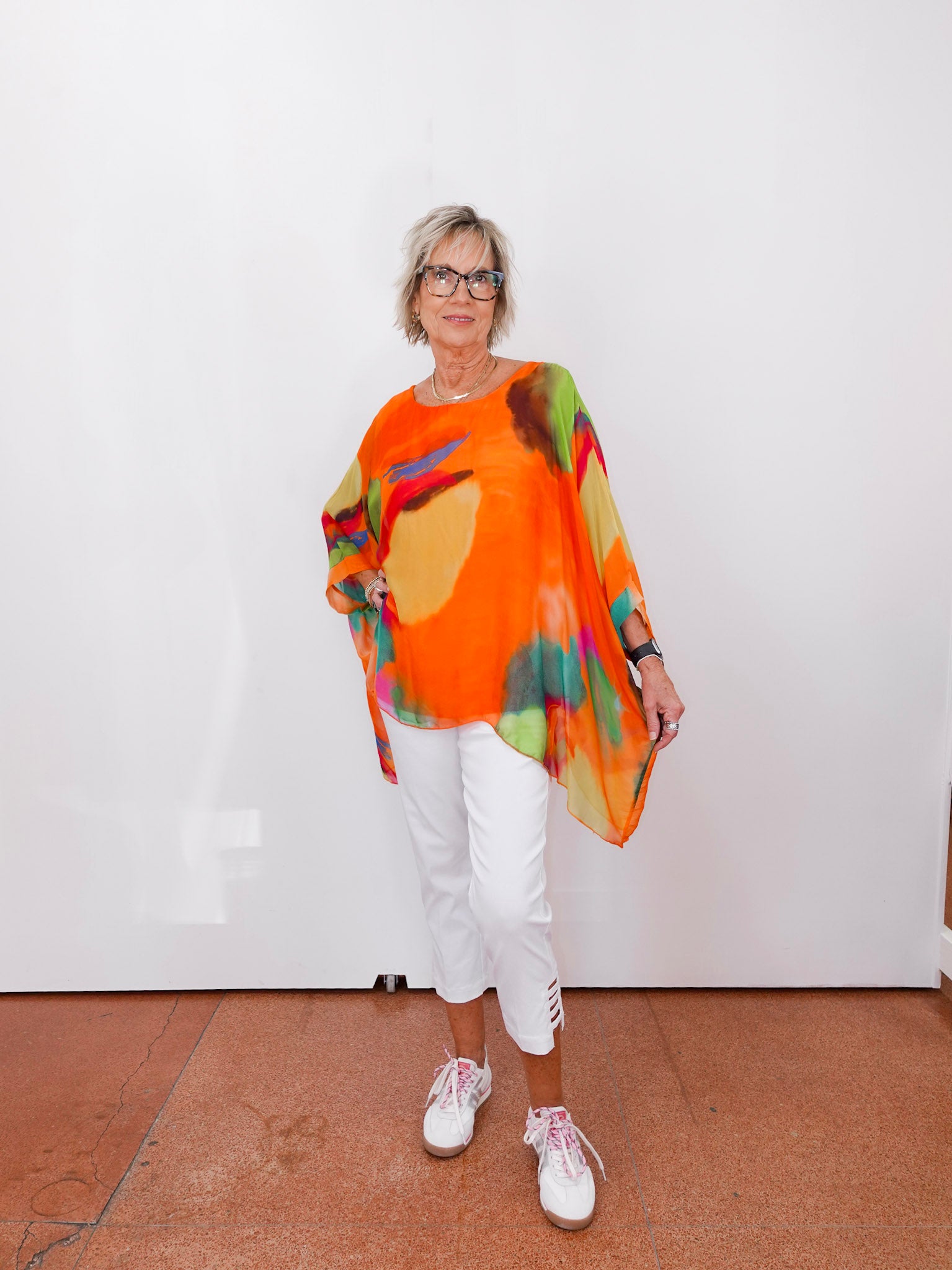 Person wearing a colorful poncho with abstract patterns against a white wall.