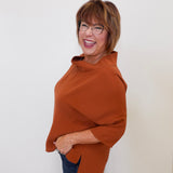 Woman wearing a brown poncho against a white background