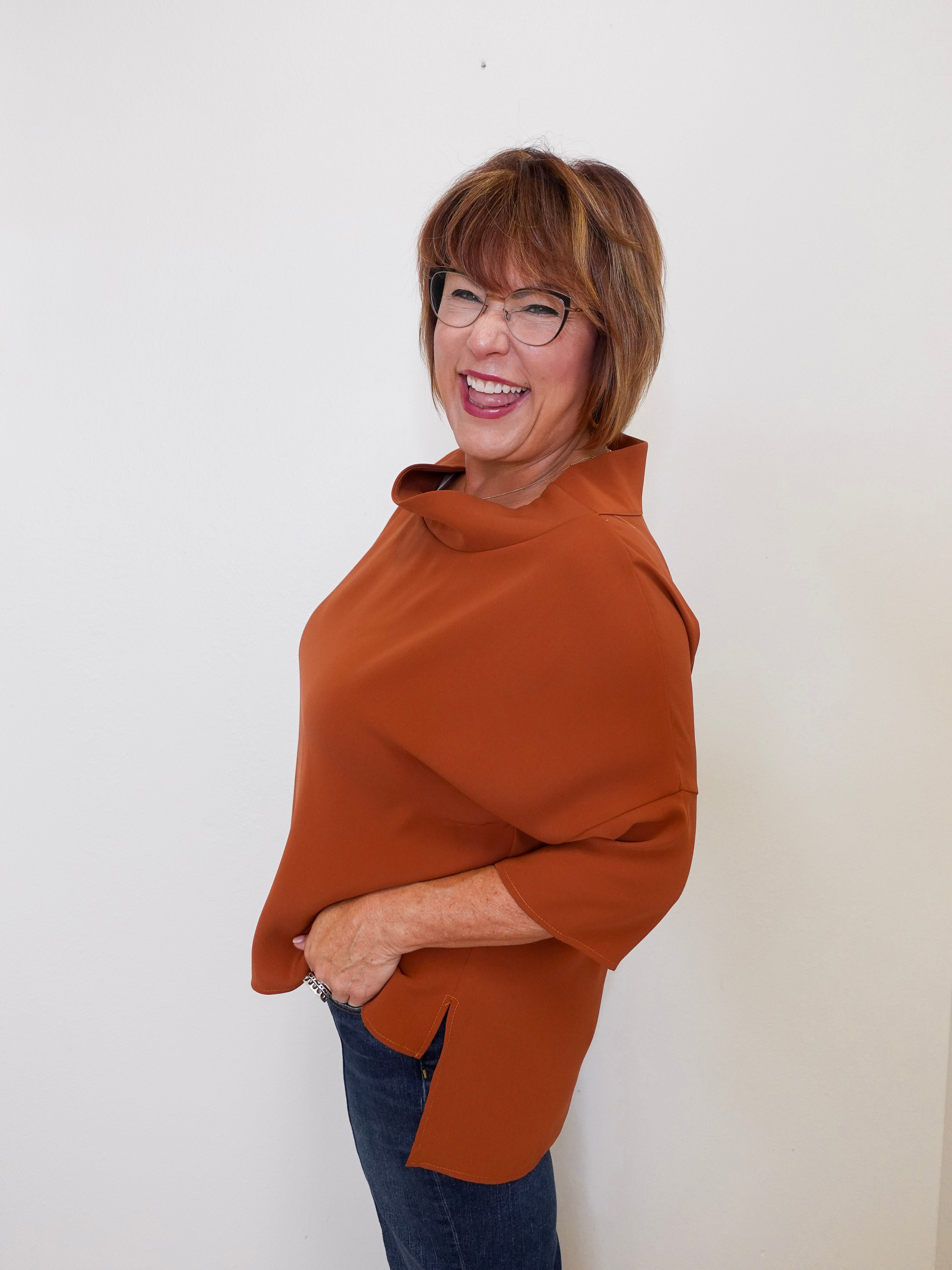Woman wearing a brown poncho against a white background
