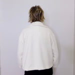 Person wearing a white jacket against a plain background