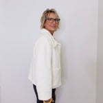 Person wearing a white coat against a plain background