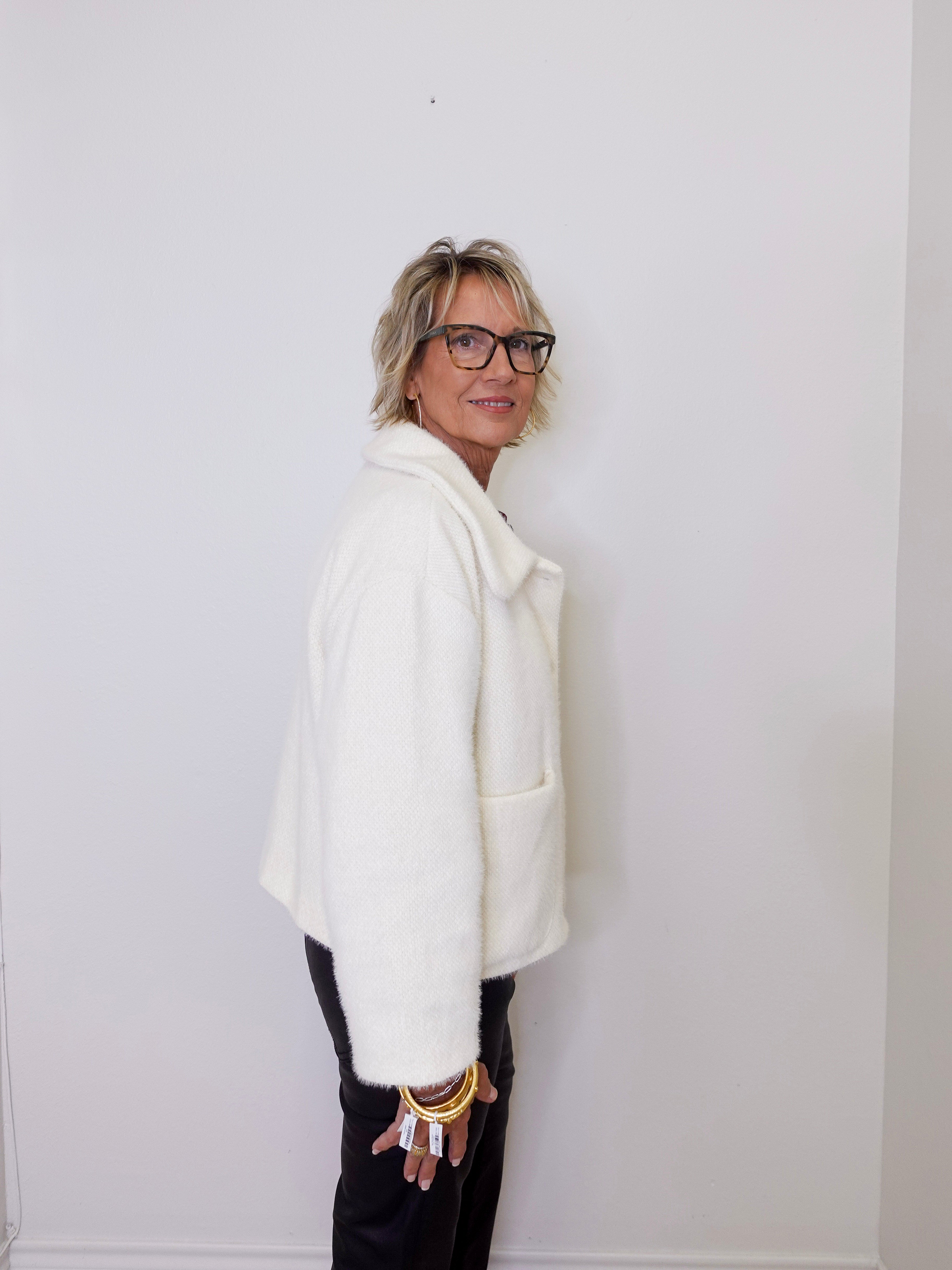 Person wearing a white coat against a plain background