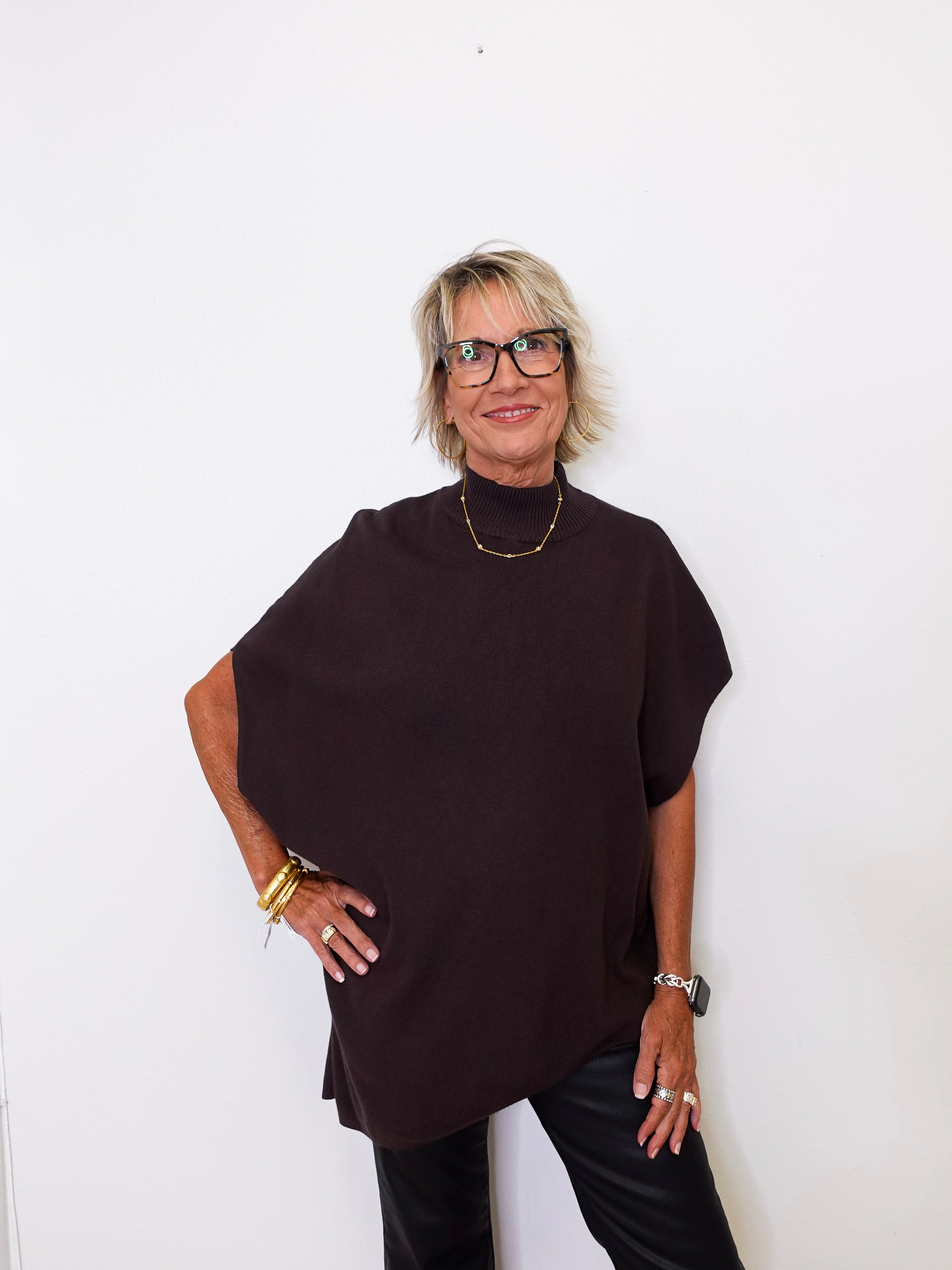 Woman wearing a dark brown poncho against a white background