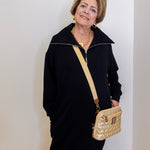Woman holding a gold handbag against a white wall