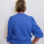 Person wearing a blue outfit against a white wall