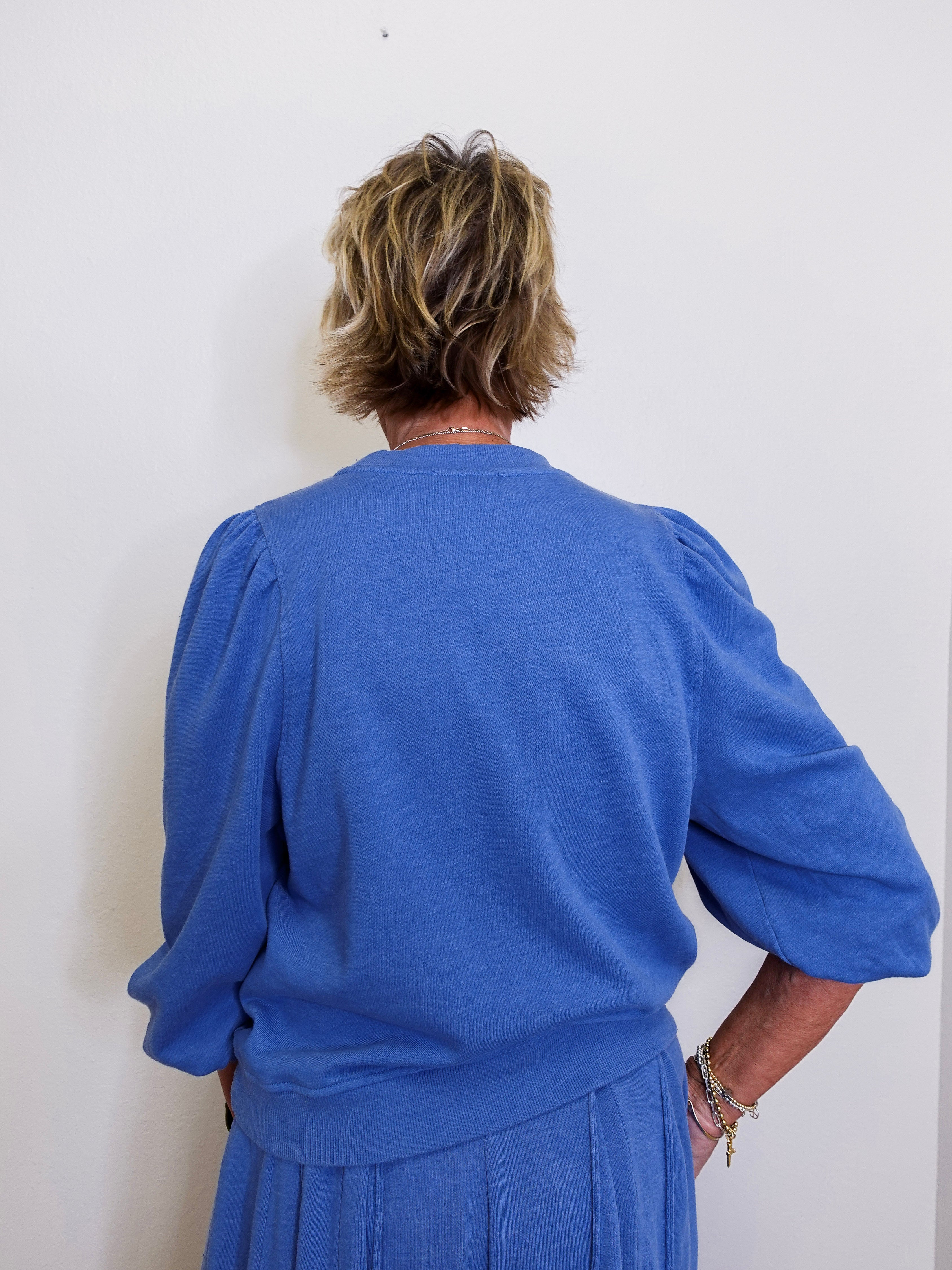Person wearing a blue outfit against a white wall