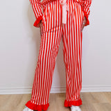 Person wearing a red and white striped outfit with ruffled pants on a light wooden floor.