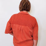 Person wearing a rust-colored shirt against a white background