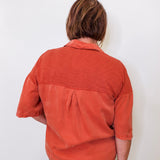 Person wearing a rust-colored shirt against a white background