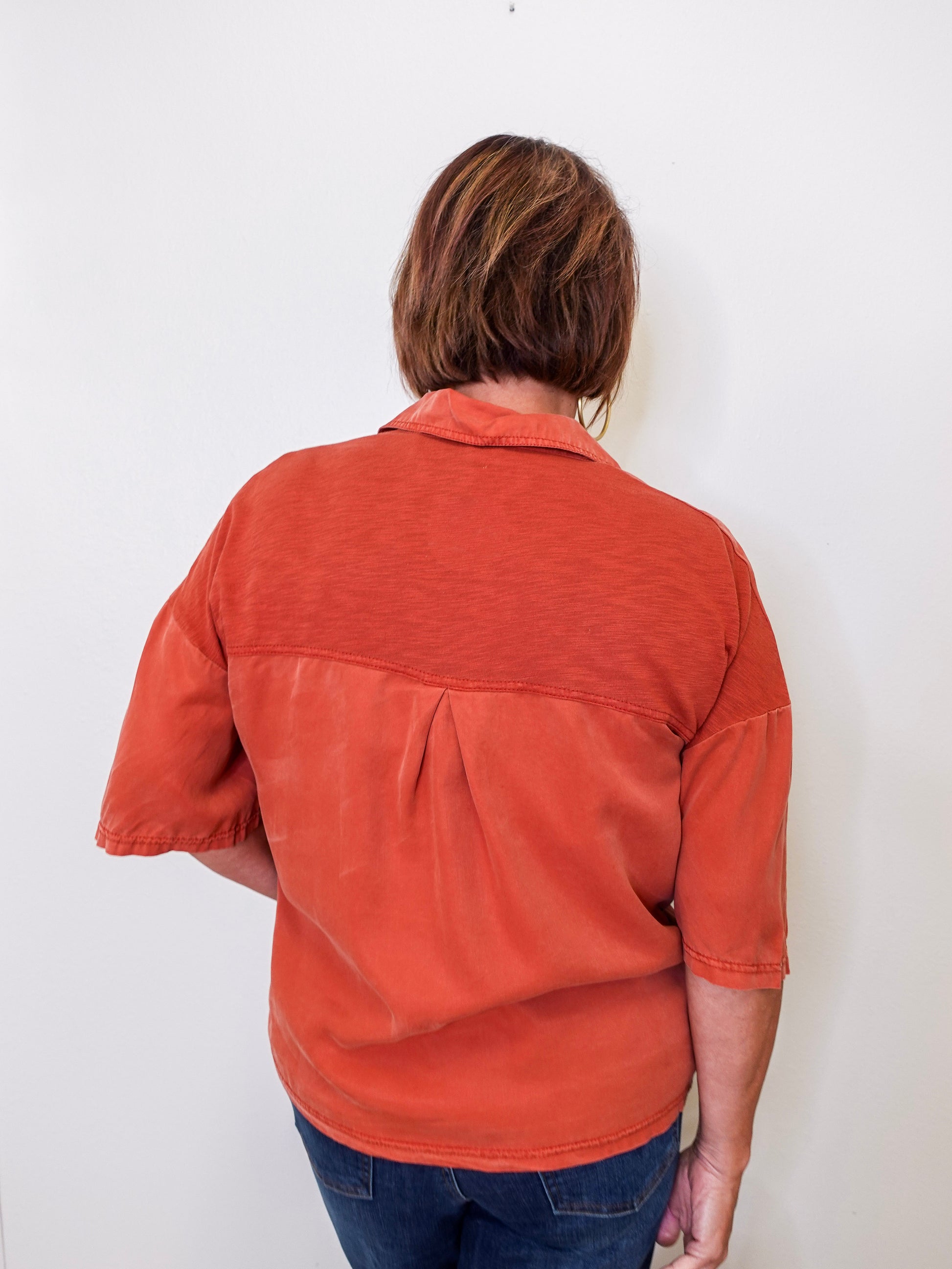 Person wearing a rust-colored shirt against a white background
