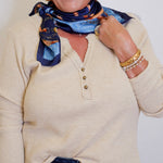 woman wearing a tan waffle knit top that is long sleeve in front of a white background. 