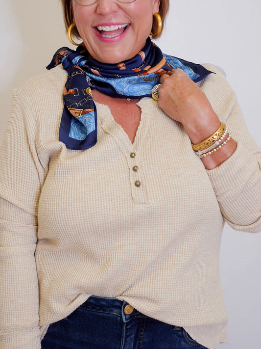 woman wearing a tan waffle knit top that is long sleeve in front of a white background. 