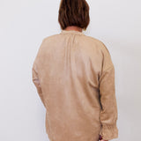 Person wearing a beige long-sleeve shirt against a white background