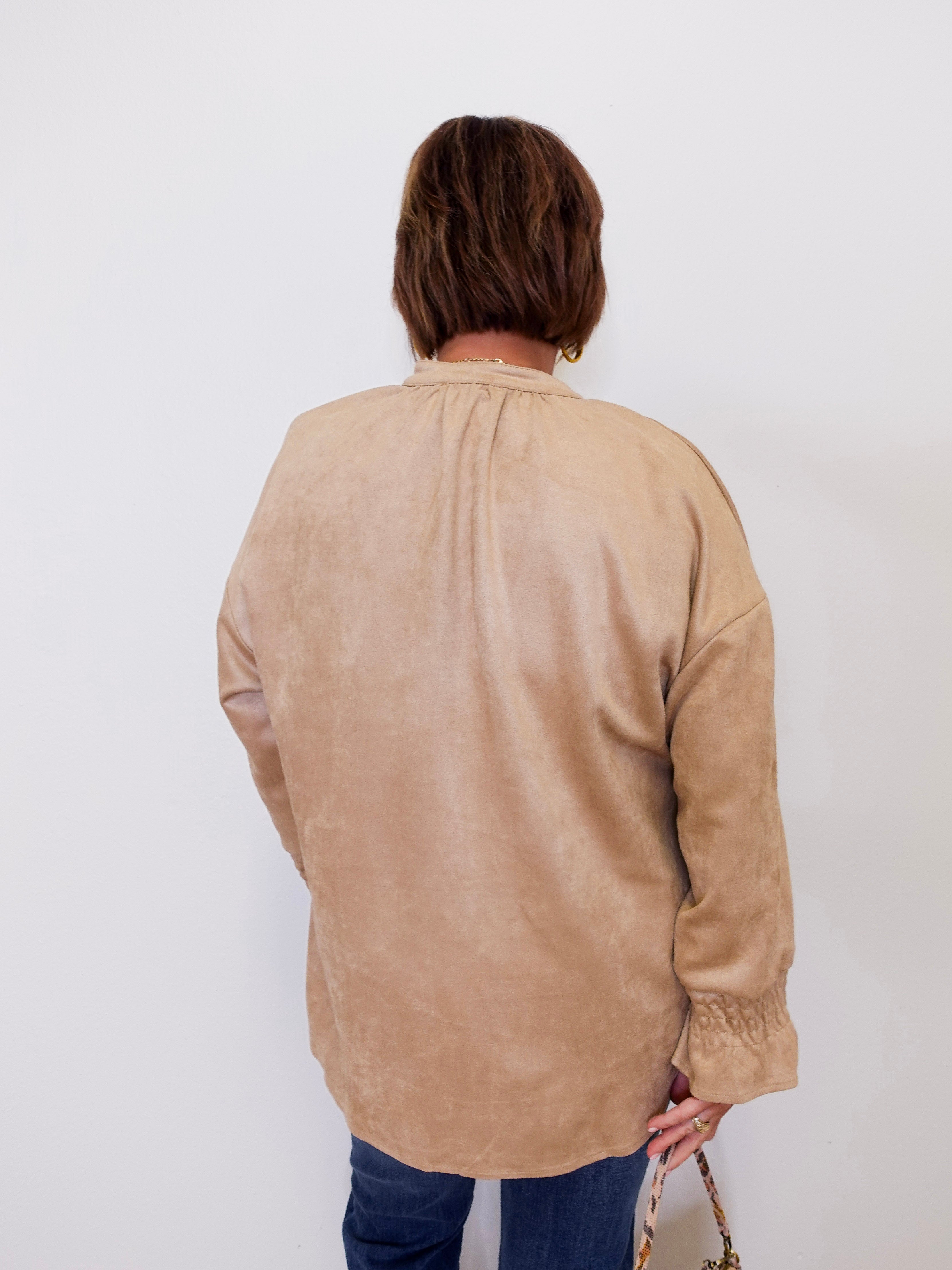 Person wearing a beige long-sleeve shirt against a white background