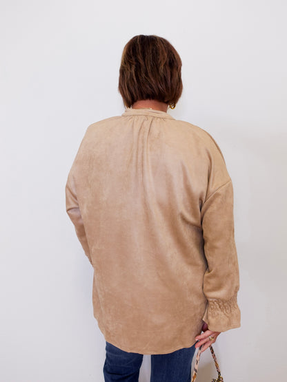 Person wearing a beige long-sleeve shirt against a white background