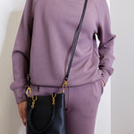 woman wearing the Black handbag with gold accents on a white background.